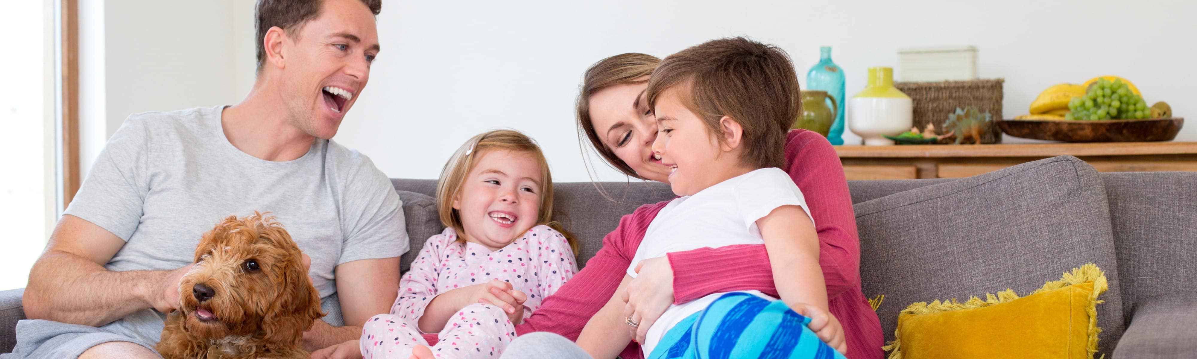 Happy family sitting on the couch with a dog.