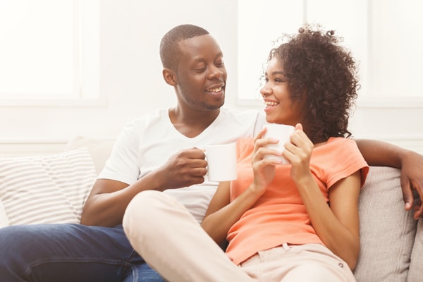 Smiling black couple drinking coffee at home.